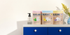 A serene navy blue countertop holding blueland tablet refills and forever tins against a grey background
