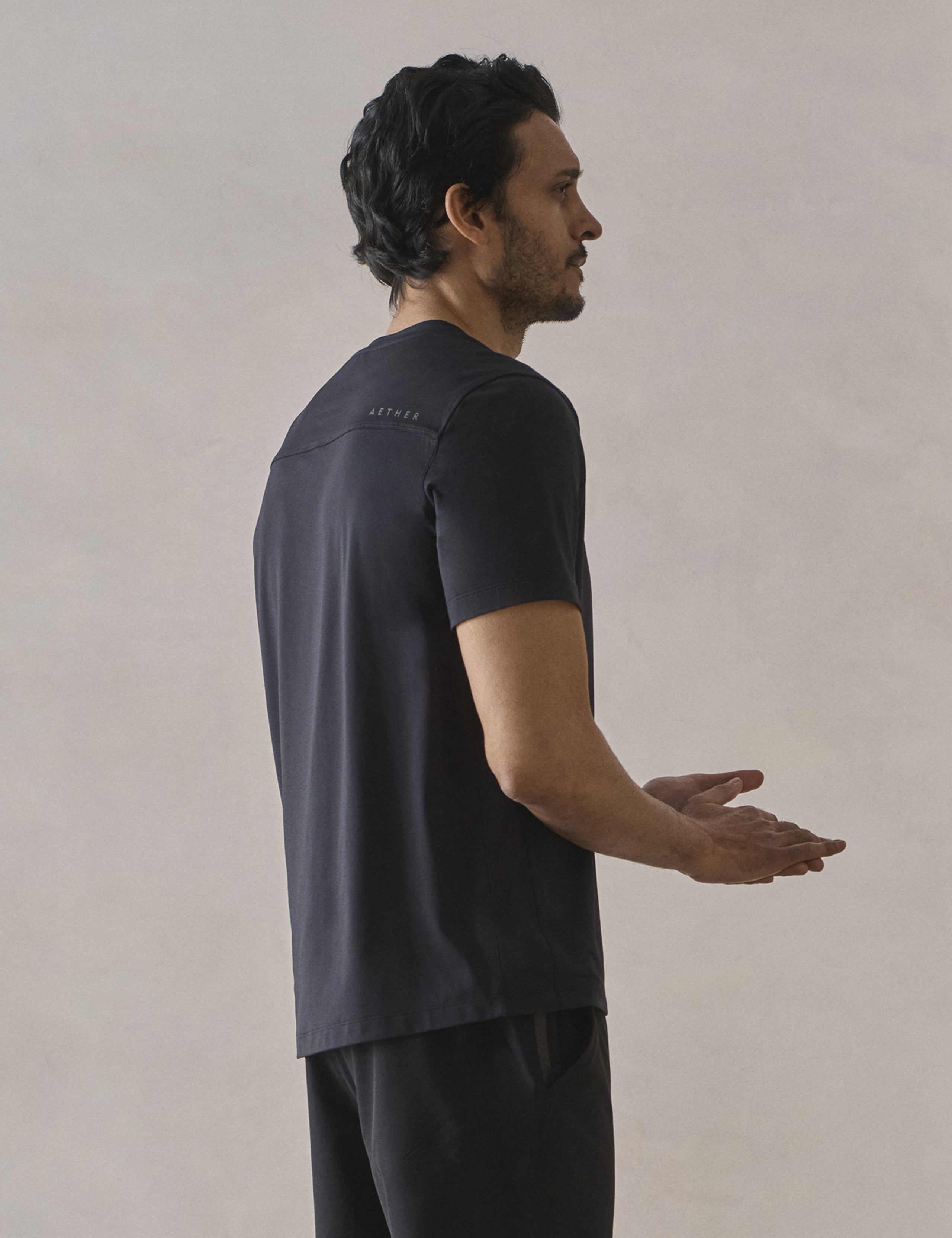 Rear 3/4 upper-body view of man wearing Adventure Performance Short-Sleeve Tee in Onyx Black from AETHER Apparel.