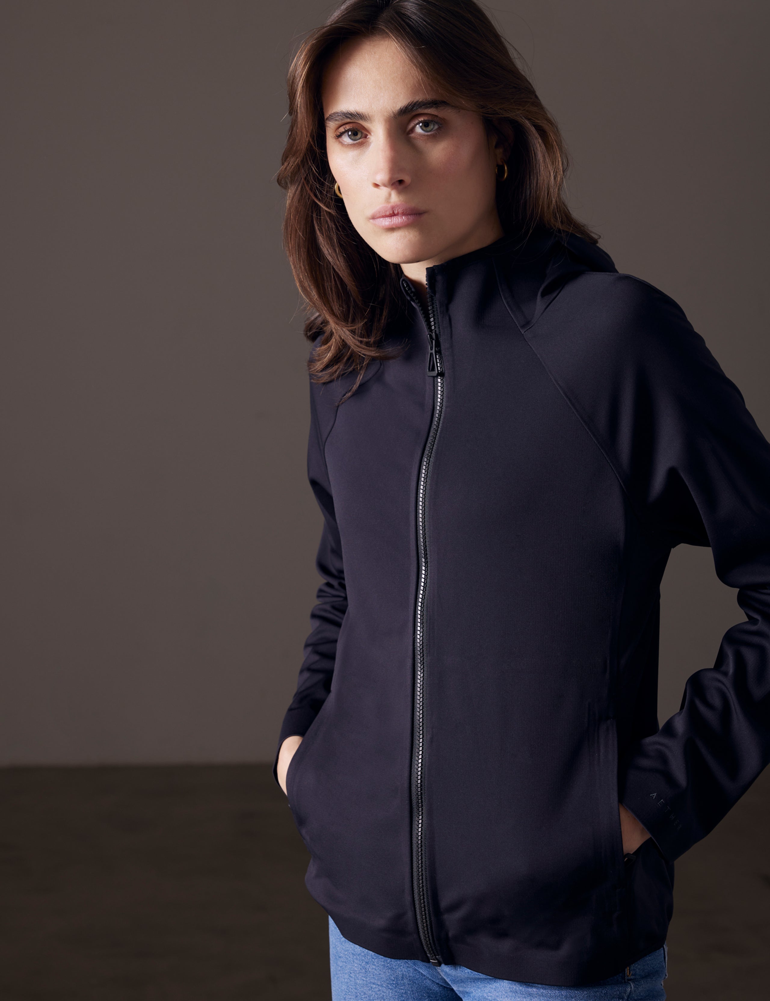 Front angled view of woman wearing Hooded Tech-Fleece Full-Zip in Onyx Black from AETHER Apparel.