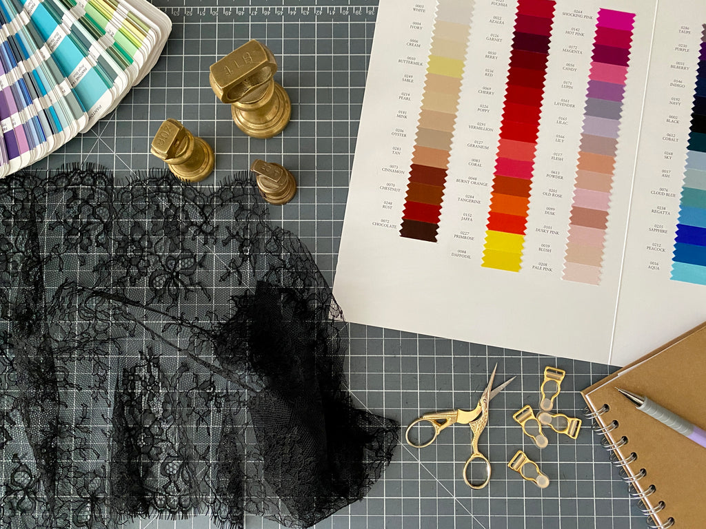 Lingerie design components, with lace, silk swatches, scissors, shade card, garter clips