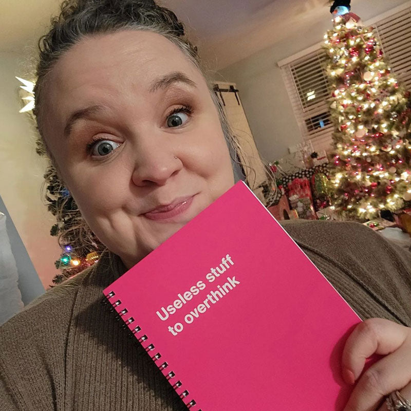 A woman laughing presenting her Christmas gift, a WTF Notebooks