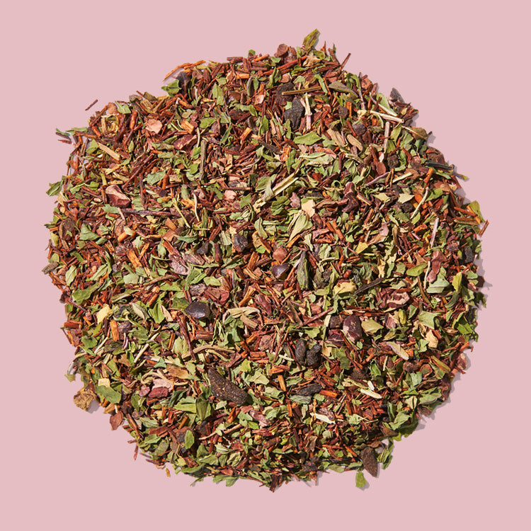 A pile of loose herbal tea leaves on a pink background.