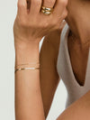 Person wearing Paper Chain Bracelet with miniature gold links, showcased on their wrist, highlighting its elegant design and fashion-forward appeal.
