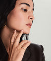 Woman with hand on chin, showcasing the Eternity Line Band, a handcrafted 14k gold ring, featuring elegant pleats.