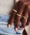 Wishbone Stacker Set on a hand, featuring gold rings elegantly displayed on fingers with close-up details of additional rings and a bracelet.
