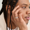 Man with braids holding his face, showcasing the Slim Rectangular Signet Ring on his finger. The ring is bold and substantial, fitting the bold jewelry agenda.