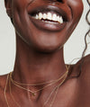 Close-up of a smiling woman wearing a chain necklace with a gold letter charm.
