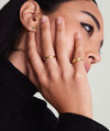 Woman showcasing Bold Stacker gold ring with diamonds on her finger, hand on face. Perfect for daily wear and matching with other Stacker rings.