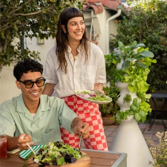 Two people enjoying a meal outdoors with fresh salads.