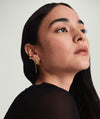 Woman wearing Dôme Hoops, gold earrings with a classic, bold design, looking to the side. Suitable for pairing with daintier rings for a stylish stack.