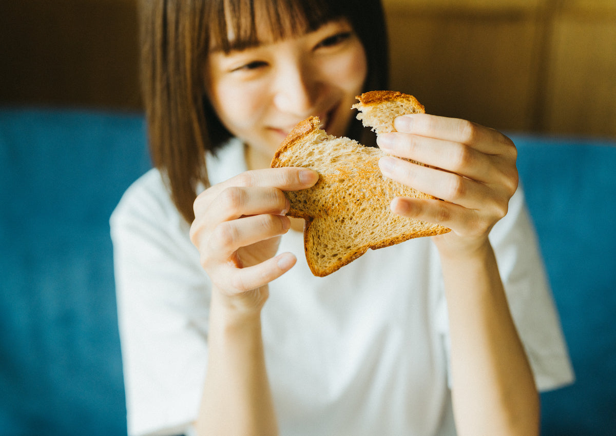 ふすまパンをちぎっている女性