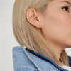 Close-up of a woman's ear wearing Tube Huggie Hoops with a clicker closure, showcasing the modern, lightweight design of the bold hoop earrings.