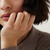 Close-up of a woman touching her chin, showcasing a handcrafted 14k solid gold Wishbone Ring on her finger.