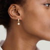 Close-up of a woman's ear wearing a Single Pearl Hoop Charm, showcasing the elegant jewelry piece designed for personalization and versatility.
