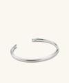Slim Cuff: A silver bracelet with a simple silhouette, featuring a letter M charm, ideal for versatile styling.