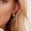 Close-up of a woman's ear wearing the Charlotte Bold Hoops, showcasing the elegant, gold earring design inspired by French dessert artistry.