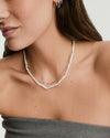Phoebe Pearl Necklace on a woman's neck, featuring elongated stick pearls, capturing an elegant and refreshing style perfect for a sunny day.