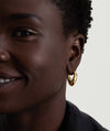 Close-up of a woman wearing the Dôme Figure Hoops, showcasing the sculptural 18k gold vermeil earrings that enhance her elegant look.