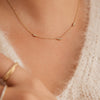Person wearing the Floating Sapphire Necklace, featuring a gold chain and sparkling sapphire-studded pendant, highlighting its elegant design and luxurious appeal.