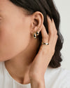 Close-up of a woman's ear adorned with Dôme Hoops, showcasing their bold, classic design. A finger with a ring is gently touching the earring.