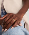Close-up of a hand wearing the 14k solid gold Duo Ring, featuring two thicker, intertwined bands.