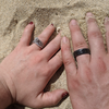 A husband and wife show of their rings in the sand